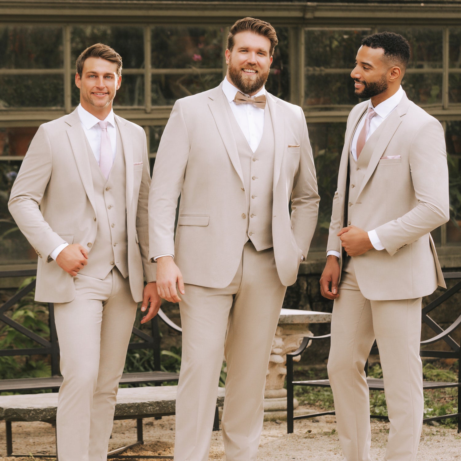 Three groomsmen in tan three-piece suits with blush ties